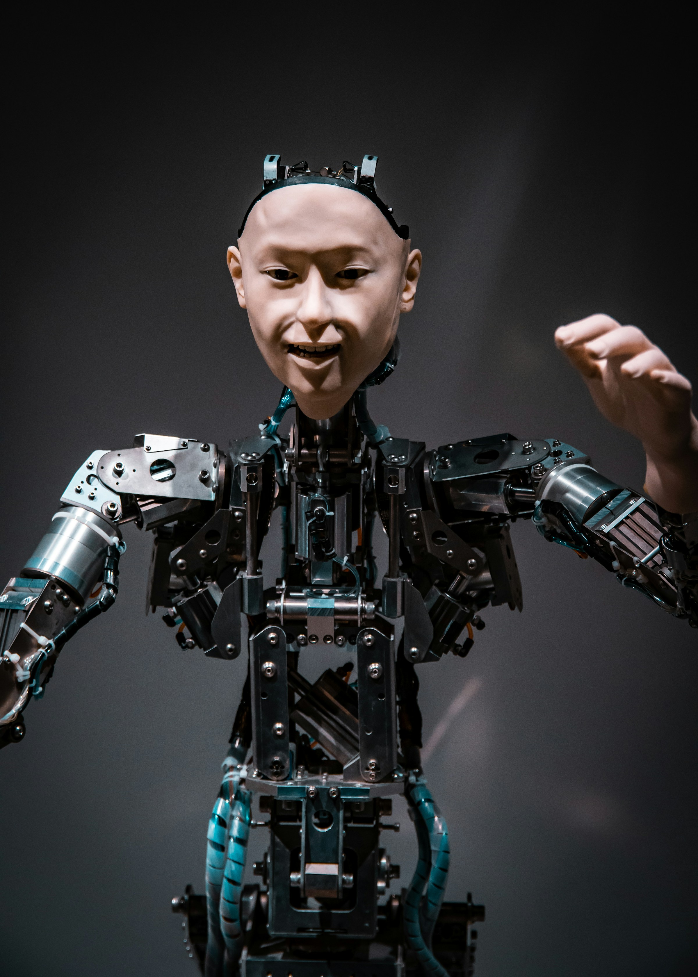 A humanoid robot standing in a dark studio, lit from one side.